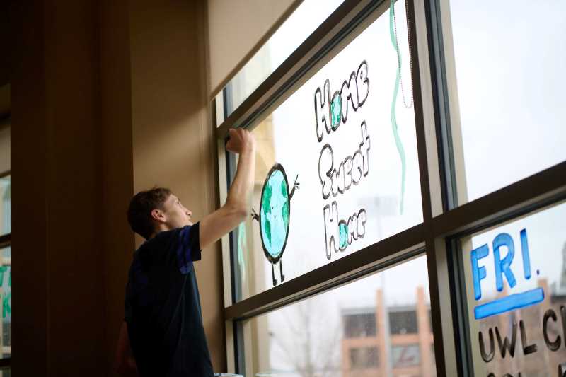 A student paints on a UWL Student Union window for Earth Day celebrations in 2022.
