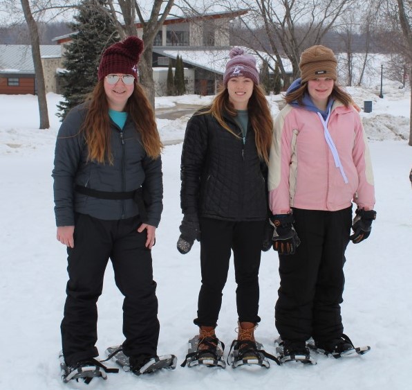 A girl snowshoes with two Mentors at Myrick Park.