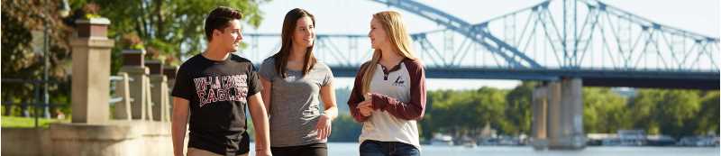Students with UWL shirts on walking in Riverside Park  in front of the Mississippi River bridge.