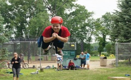 Young man has fun on the ropes course during a mentoring activity.