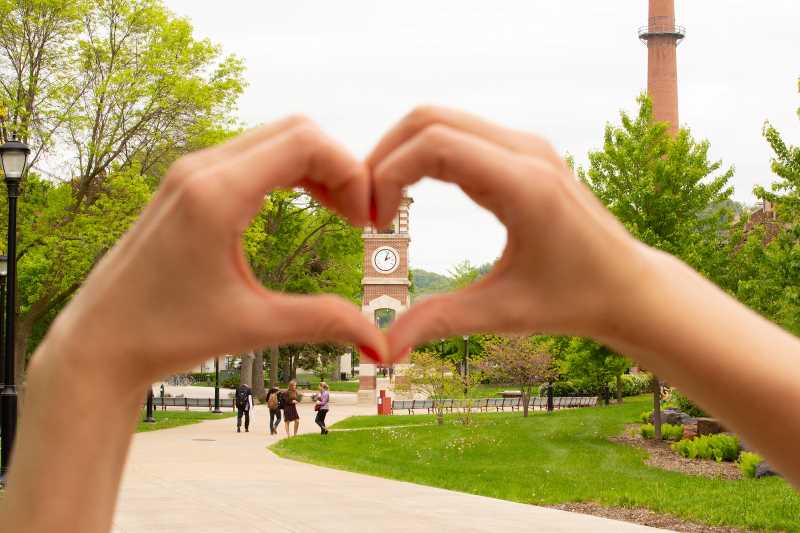 Hands creating a heart shape around UWL's clocktower