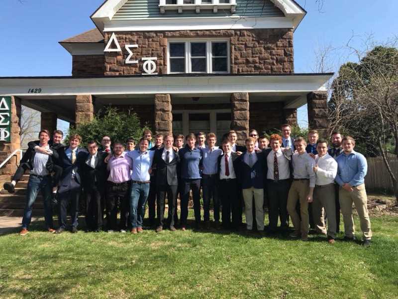 Members of Delta Sigma Phi standing outside of their house.