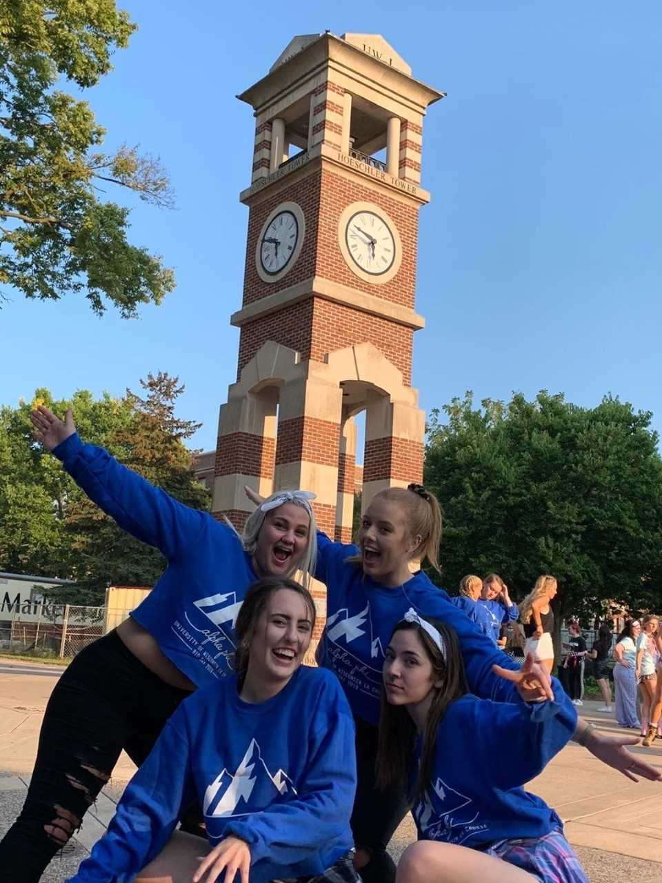 A group of Alpha Phi members pose in front of the clock tower in their matching bid day sweatshirts. 