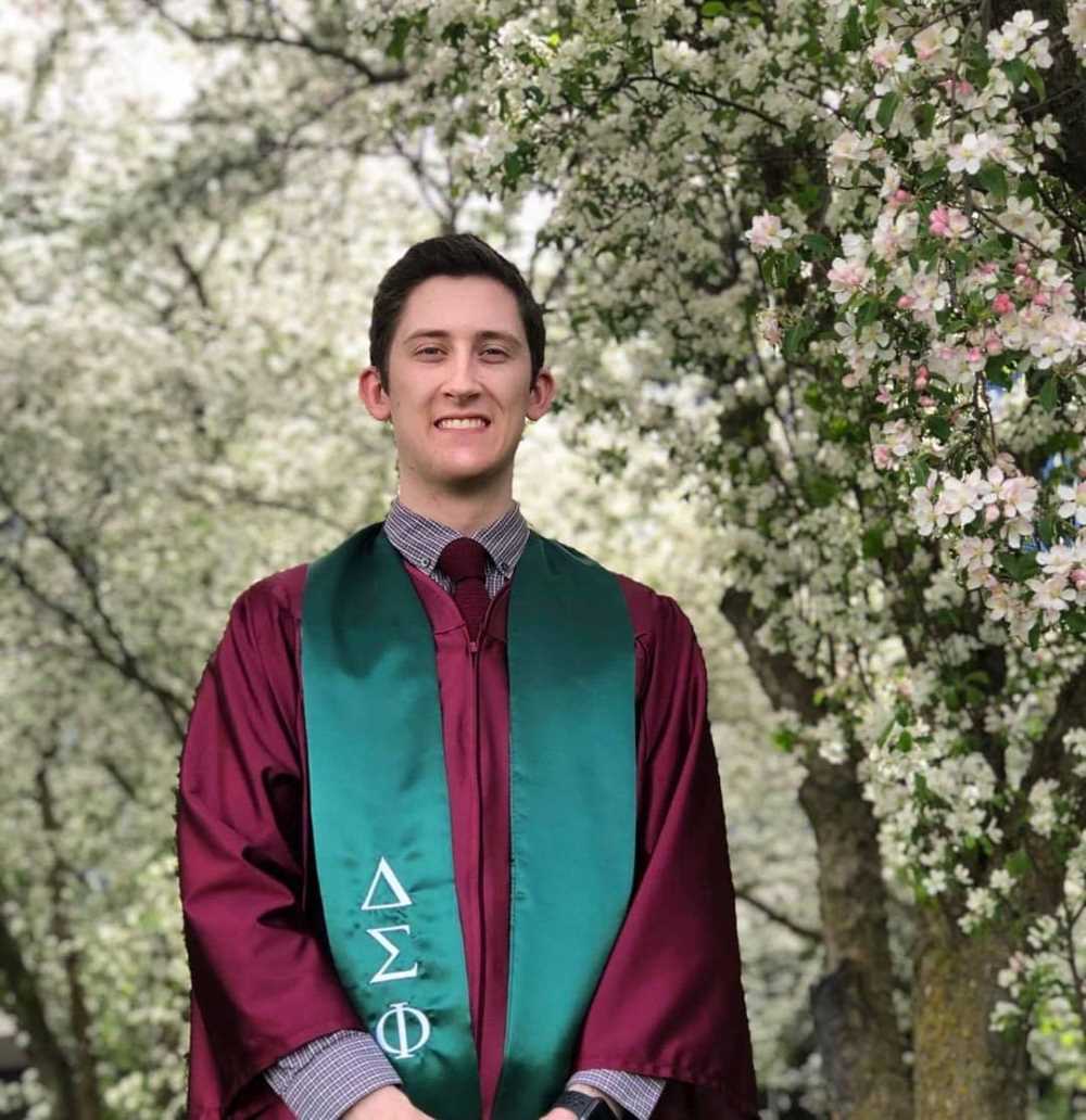 A fraternity member has his photograph taken wearing the Delta Sigma Phi graduation stole. 