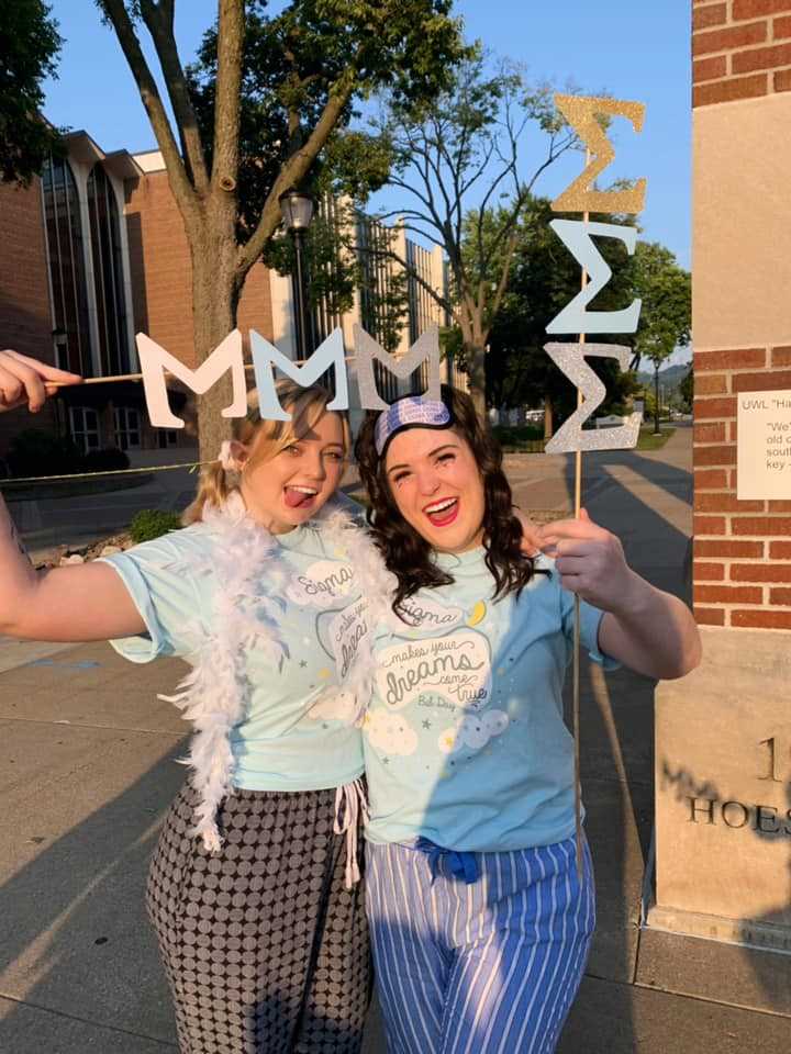 Two Tri Sigma women celebrate 2019 Bid Day waving their letters and wearing matching Bid Day shirt. 