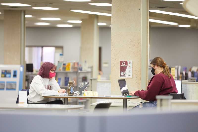 Students studying in the library while wearing masks