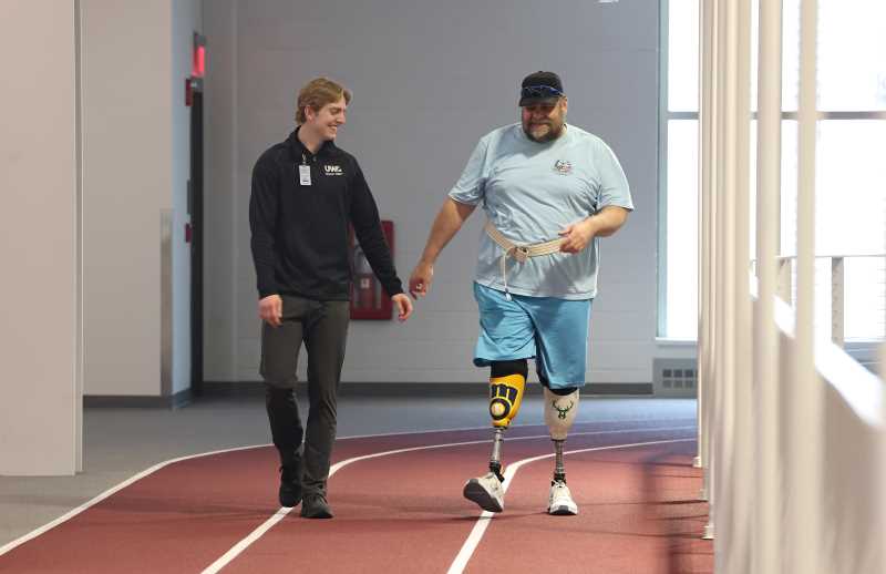 Walter Van Roo, of La Crosse, walks around the UWL Fieldhouse track with physical therapy student Casey Breunig, a volunteer for the LEAP program. Breunig was hooked after his first session assisting amputees with exercise plans. “This program shows there is a real need for the degree we are pursuing,” says Breunig. 