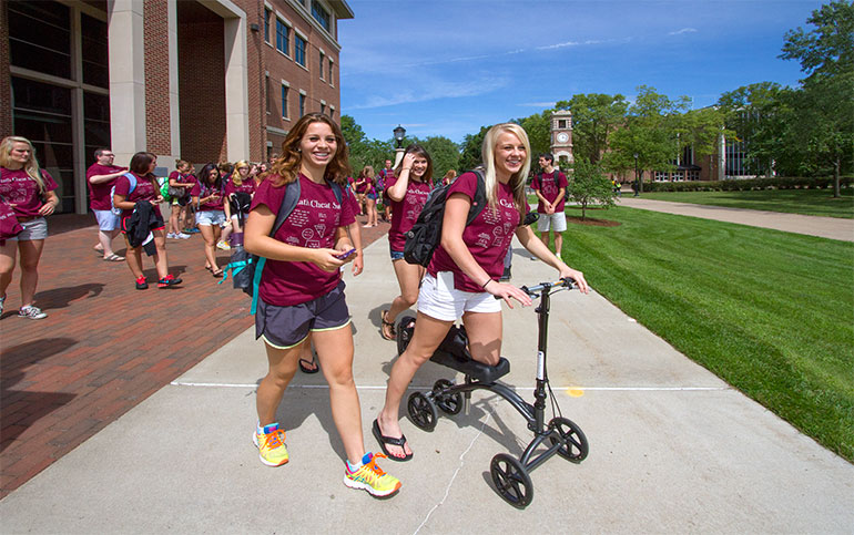 Students in maroon T-shirts.  One on scooter. 