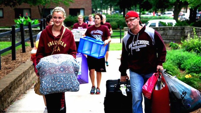 Parent and daughter carrying pillow and bags on move in day 2014