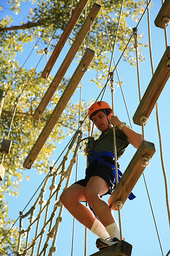 Image of a student hanging on a ropes course. 