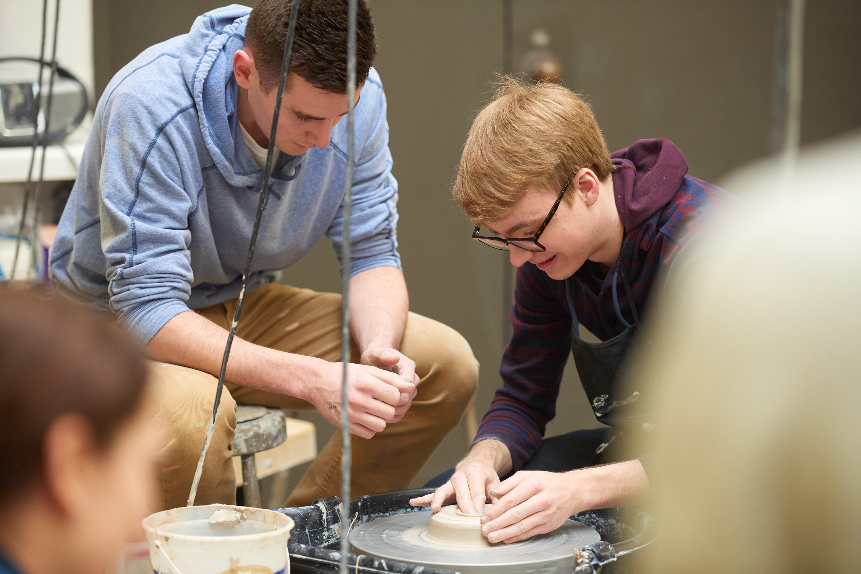 UWL student Max Scheurell, pictures left, teaches a student to use a clay potters wheel in the ceramics studio. 