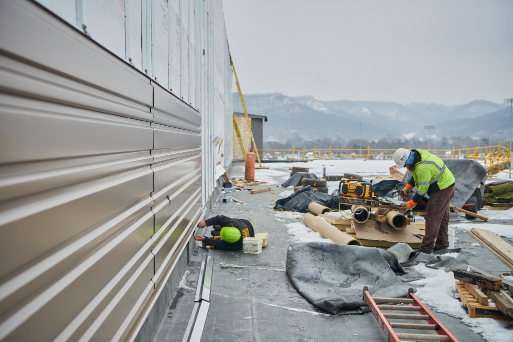 Contractors install steel siding on the south side of the student center.