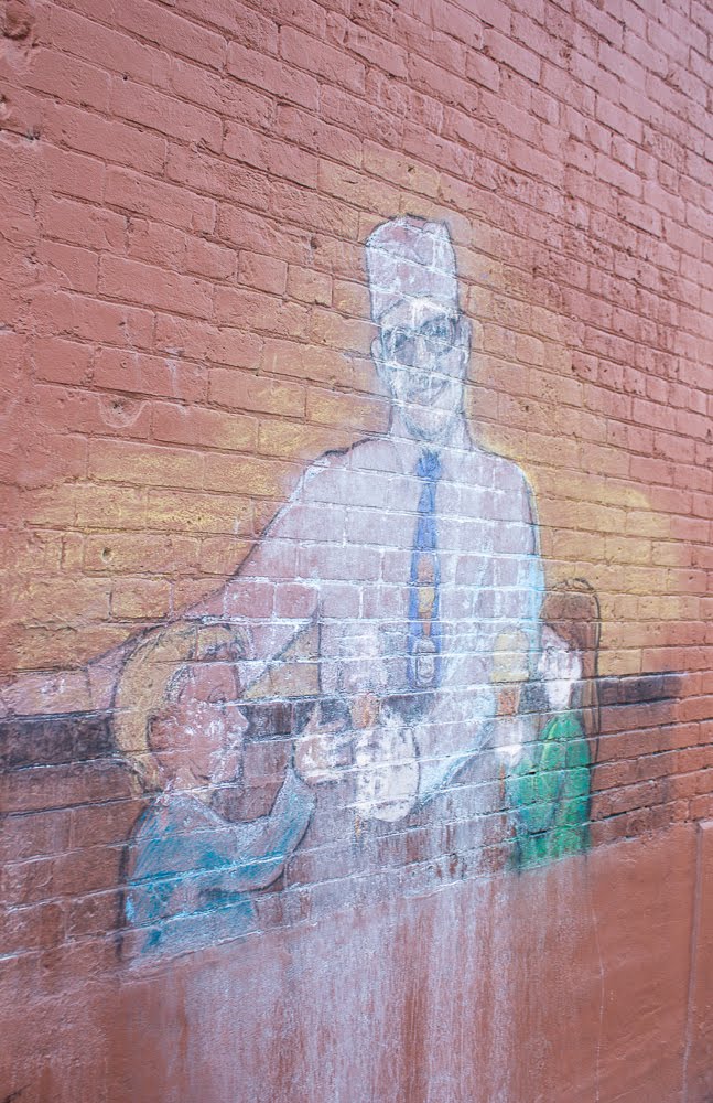 image of someone handing ice cream to children pained on the side of a brick building.