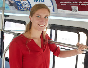 Image of Rebekah Bain standing on a city bus. 