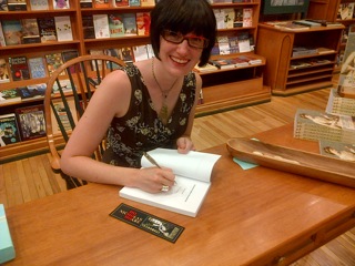 UW-L Assistant Professor Ariel Beaujot sitting at a desk writing.