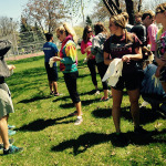 Image of students standing in grass putting their gloves on to pick up garbage.