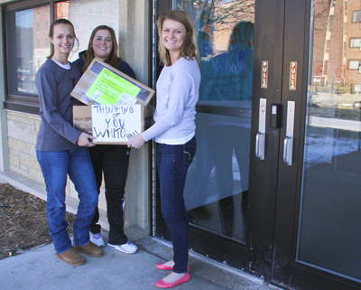 White Hall staff hold a box of goods delivered from UW-Oshkosh
