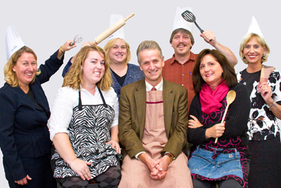 Group photo of staff with cooking utensils.