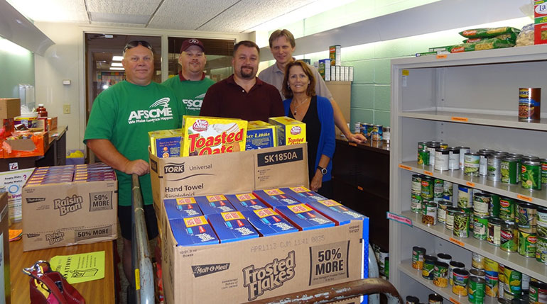 Five people in food pantry with donations of food. 