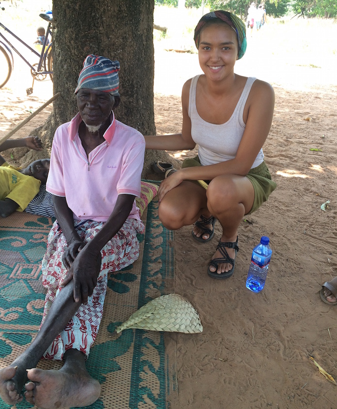 Image of Quincey Anderson sitting by the 120-year-old community member in Ghana.