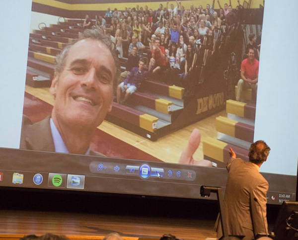 Image of Joe Gow pointing to a slide of a selfie of himself with DeSoto students. 