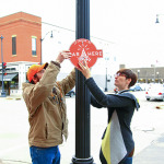 Image of Ariel Beaujot and one of her students hanging a sign on a light pole.