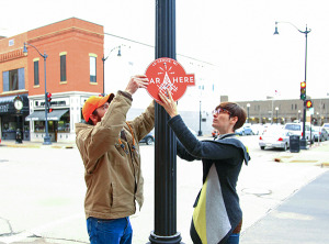 Image of Ariel Beaujot and one of her students hanging a sign on a light pole.