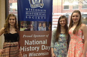 Three girls standing in front of the National History Day sign in Cartwright Center.