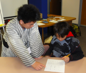 Image of Takumi Tamura teaching  Japanese calligraphy to a Logan Middle School student