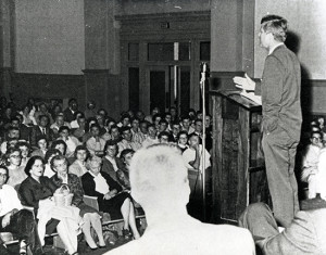 Image of J.F.K. speaking in the front of Graff Main Hall auditorium. black and white photo from 1959. 