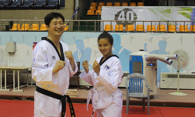 Image of Quincey Anderson in her Taekwondo class posing with the instructor.