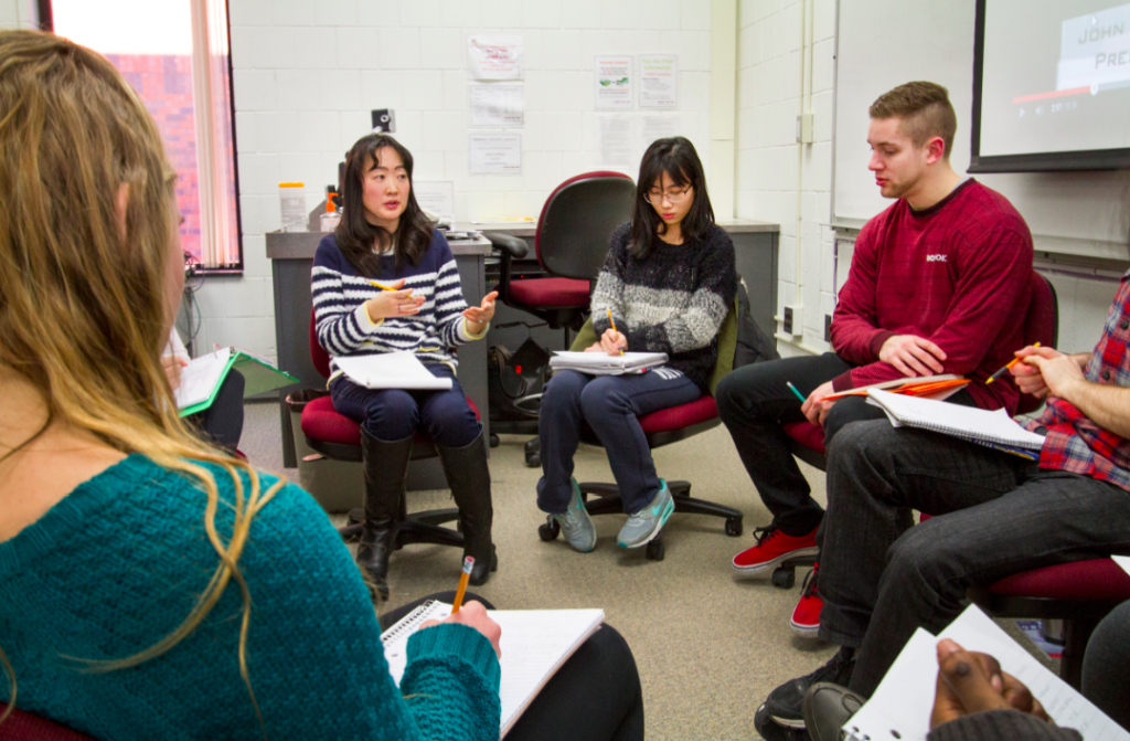 Image of Assistant Professor Lei Zhang sitting in a circle with students discussing.