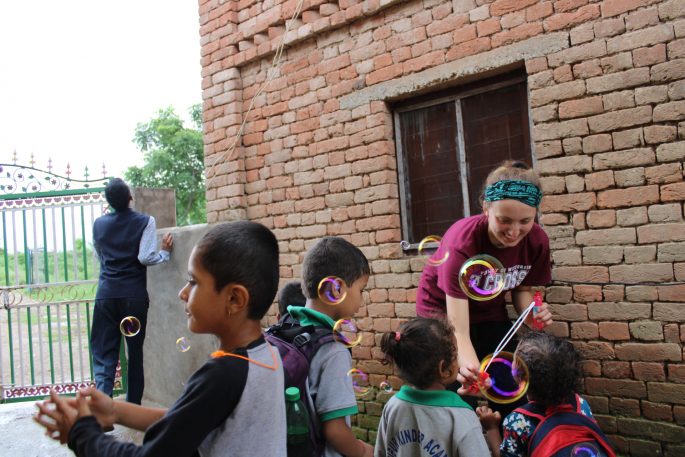 UWL senior Morgan Alexander volunteered at a school in Nepal over the summer, along with faculty member Melissa Collum. Here Alexander blows bubbles with students after school while the students wait to be taken home.  