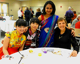 UW-L graduate Peiqing Chen sits at a table with several others at the 2013 International Banquet.