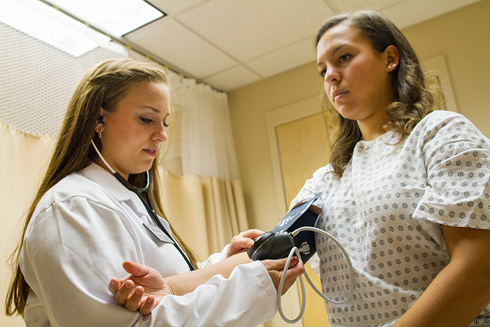 Image of one student checking the others blood pressure.