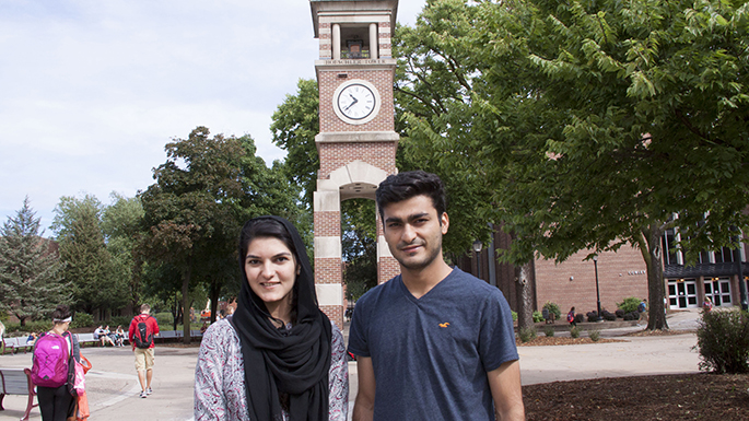 Image of the two students standing in front of the clock tower on campus.