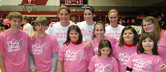 Team with students in pink on basketball court. 