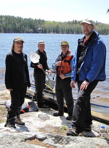 Image of people standing on the shoreline near the water of Voyagers National Park. 