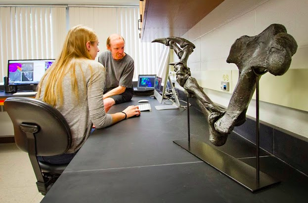 Image of Eric Snively looking at a paper with a student in his lab. 