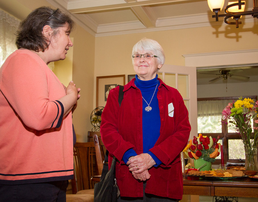 Andrea Hanson and Bonnie Pickett talking in a dining room setting.