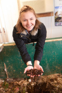 Andrea holding a handful of worms and dirt.