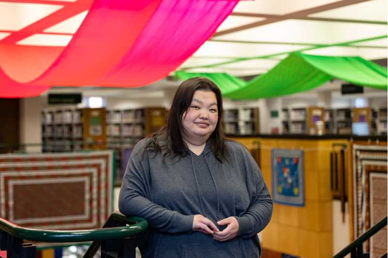 UW-La Crosse English Major Yia Vue at the Hmong culture exhibition she organized at the La Crosse Public Library. Previously a tech/digital producer in New York City, Vue recently returned to school to pivot in her career.