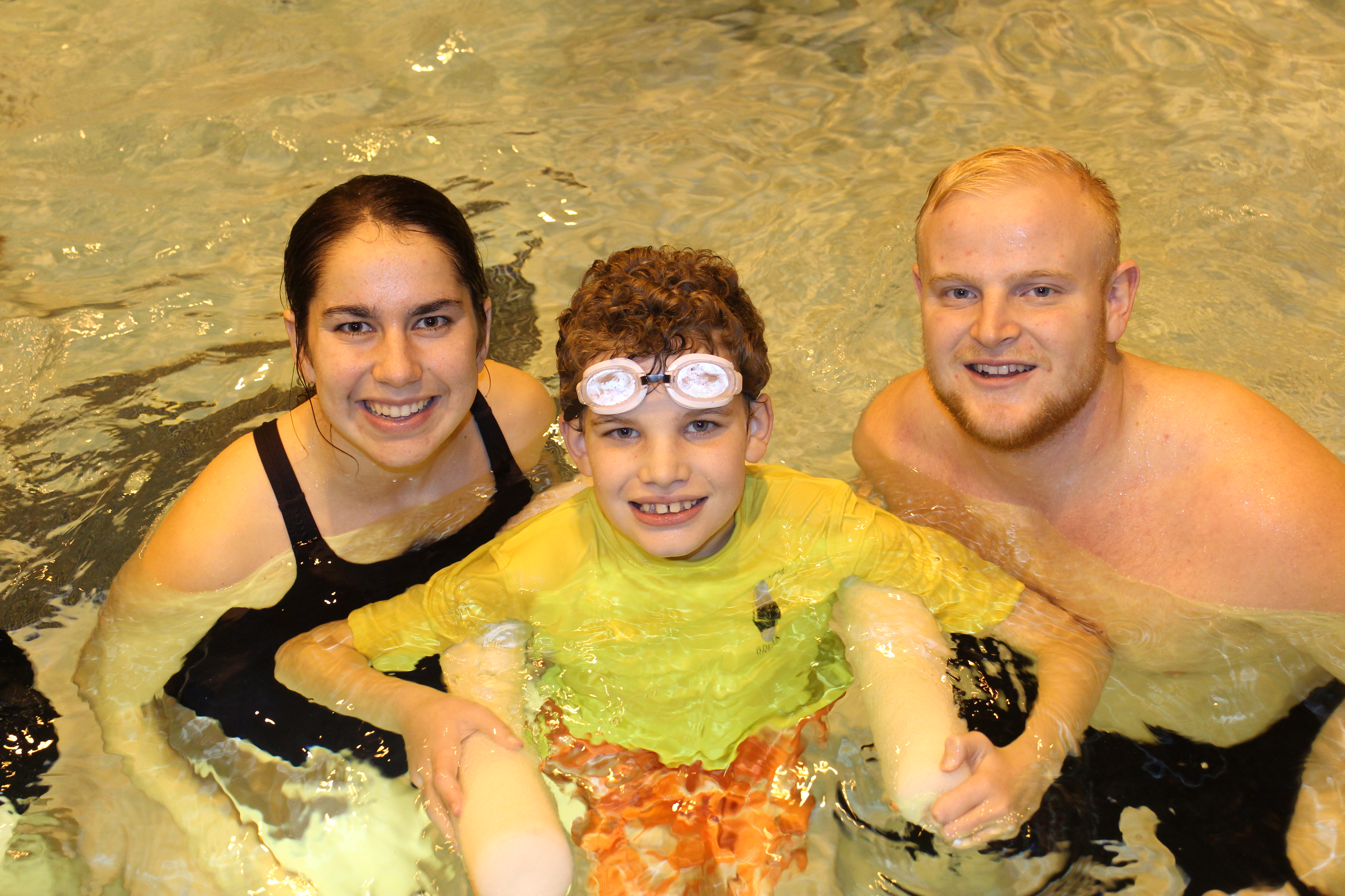 Two Adapted Physical Education Teaching Minors help a boy in the pool.