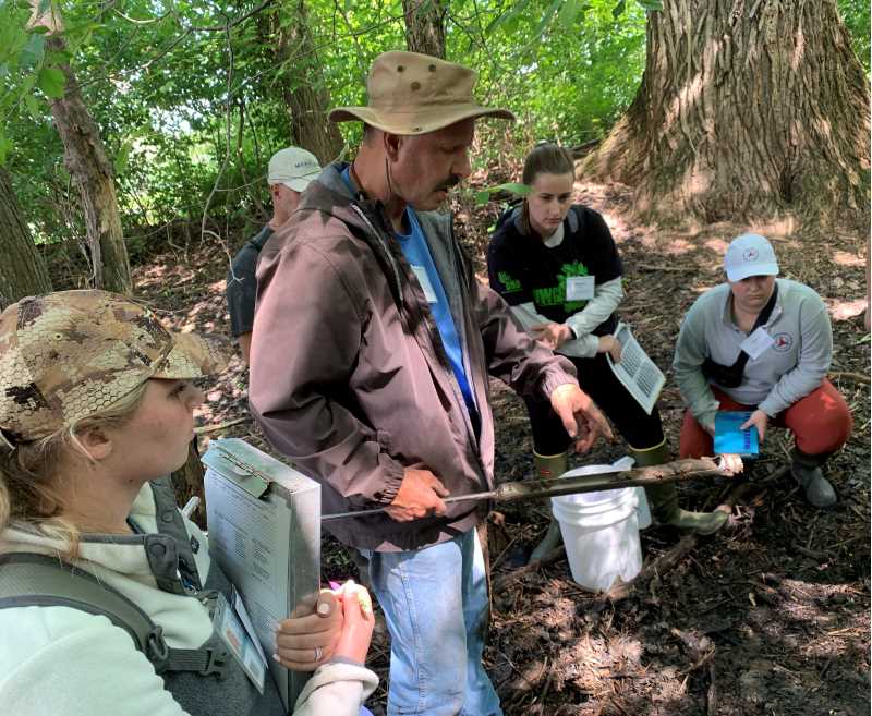 Wetland delineation workshop students work in the field with soil samples.