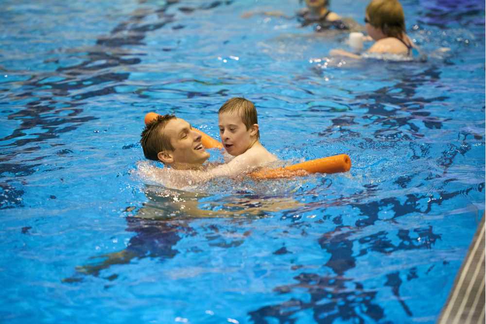 Student and youth swimming with pool noodle