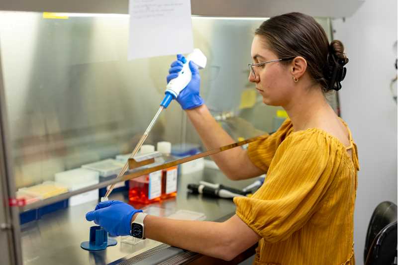 Biology graduate student working in the hood.