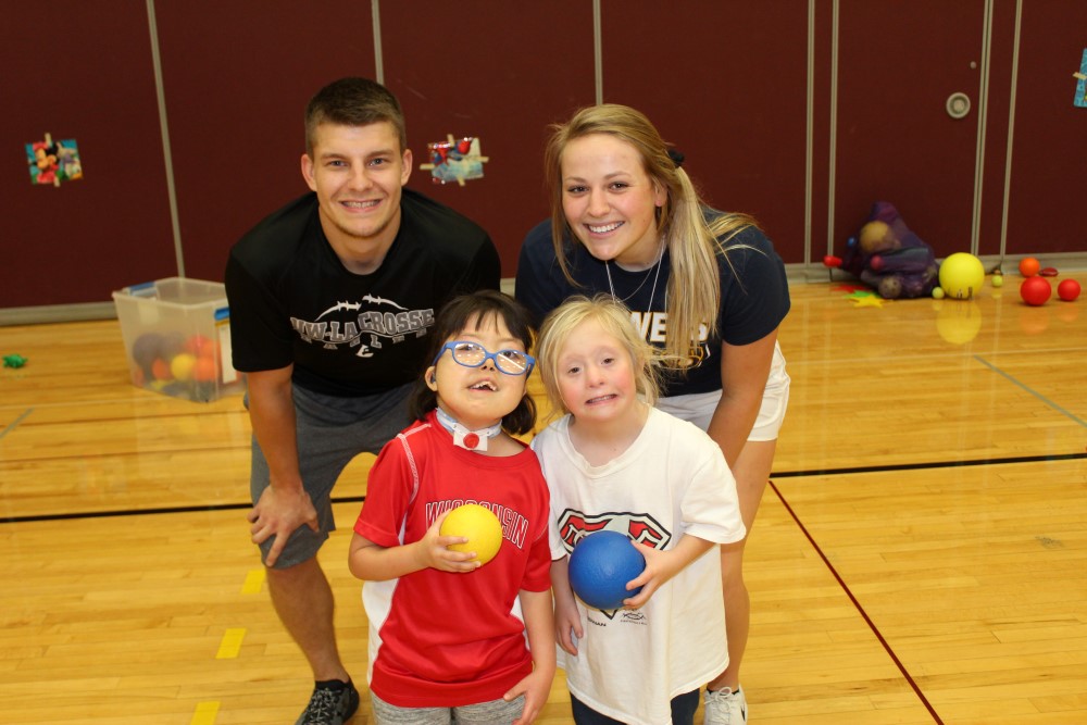 Two Adapted Physical Education Minor students play ball with two girls with disabilities.